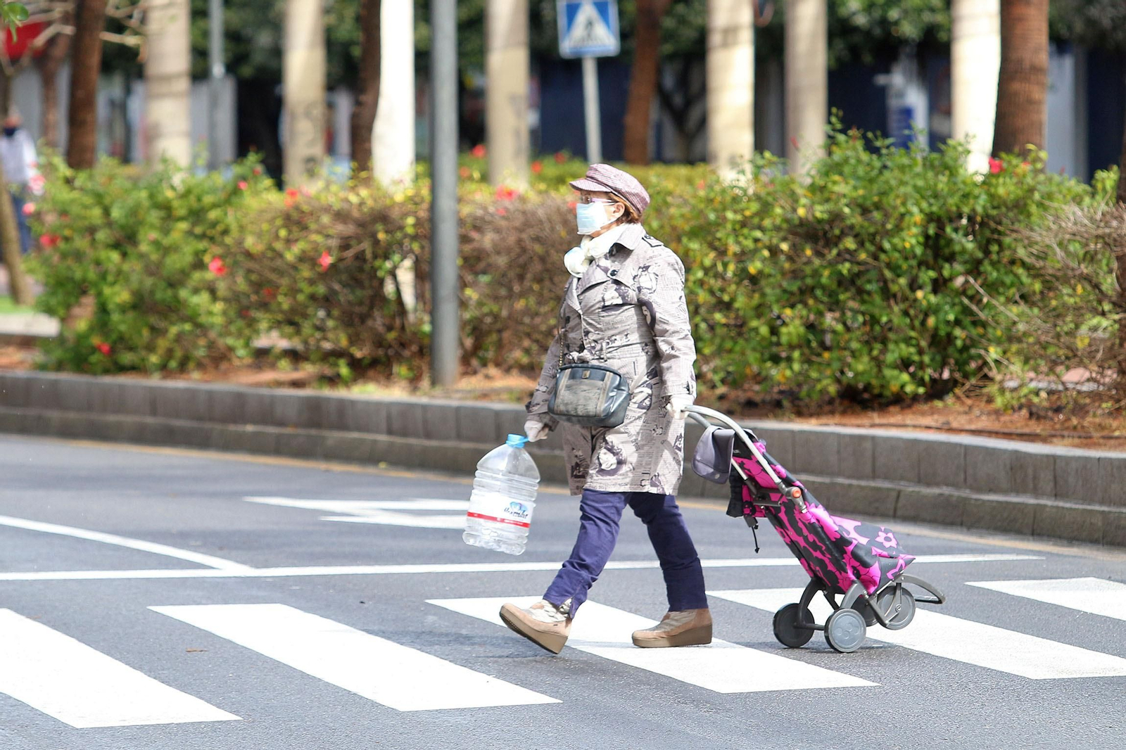 Una mujer con mascarilla cruza un paso de peatones en Almería.