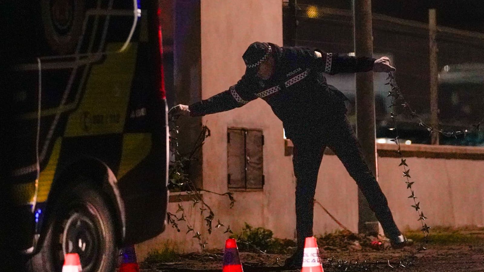 Un policía local extiende la cadena de pinchos para impedir el acceso a los vehículos a la gasolinera de Alcosa.