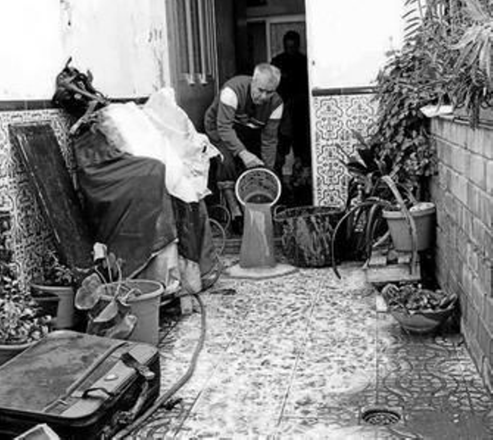 Un vecino de Pedregalejo achica el agua que inundó su casa.