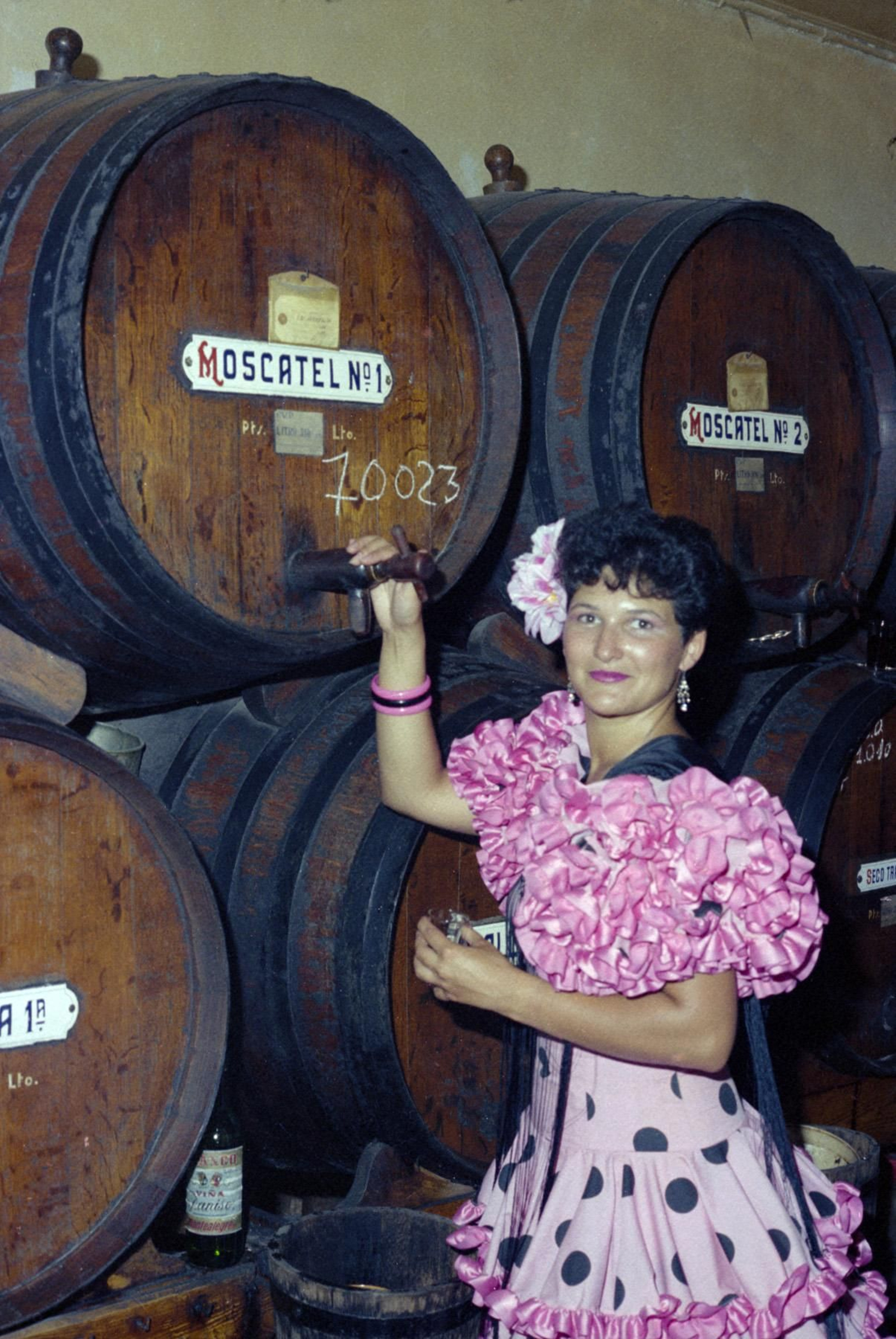 Una mujer junto a varios barriles de la bebida protagonista de la Feria, el moscatel