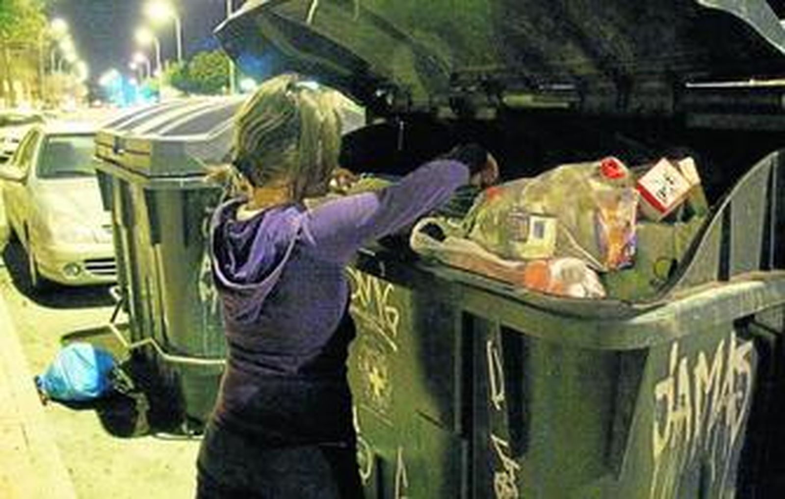 Una joven inmigrante busca algo de comer en los contenedores. Esta estampa se repite diariamente en la zona.