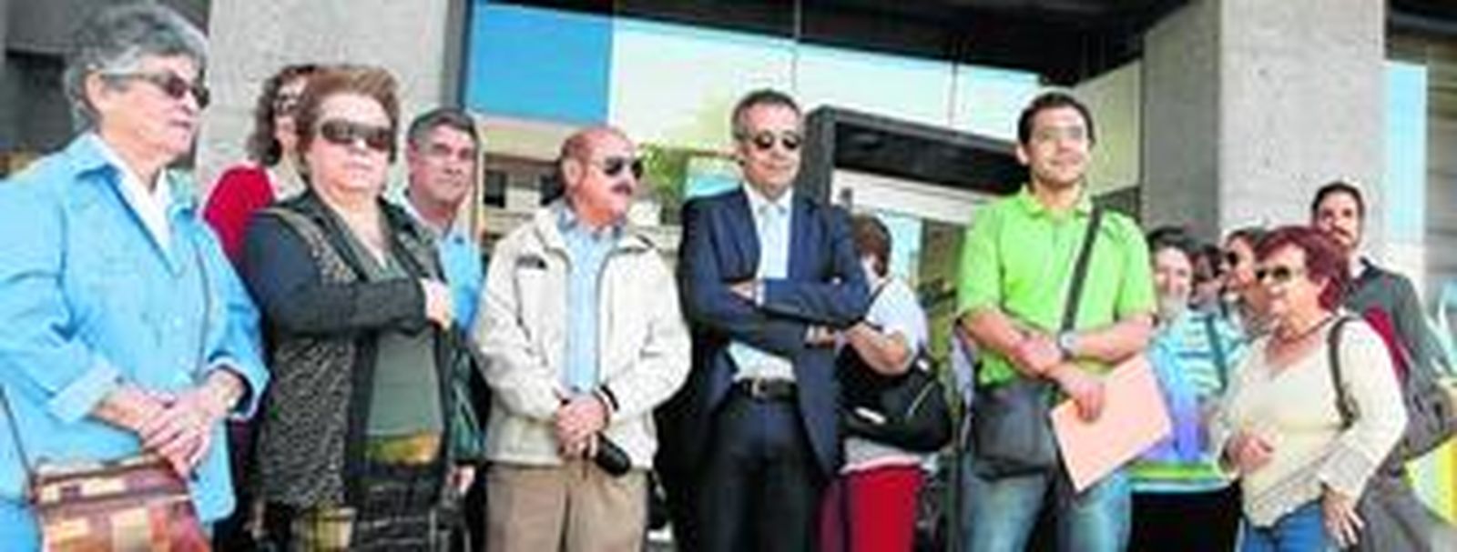 En la imagen, varios de los afectados posando ante la puerta de la sucursal de la entidad bancaria que renegocia el crédito con la promotora.