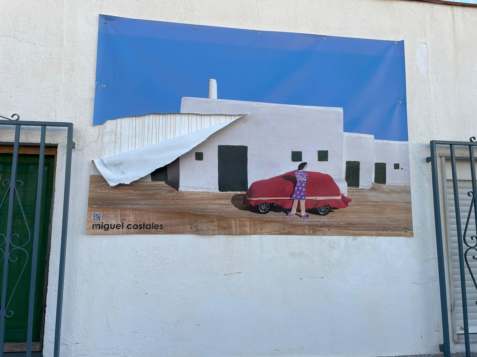 Una de las lonas de Rodalquilarte que ha sido rajada en la fachada donde se ubica.