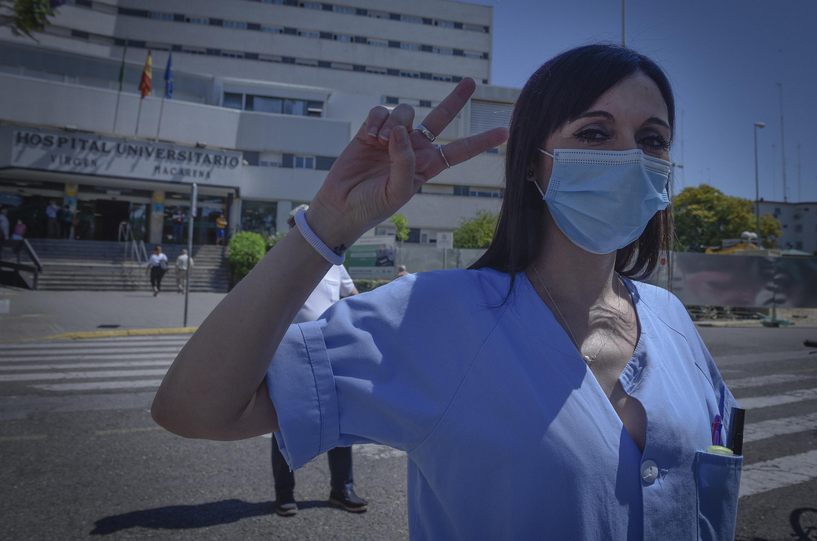 Una sanitaria muestra con su mano el símbolo de la victoria.