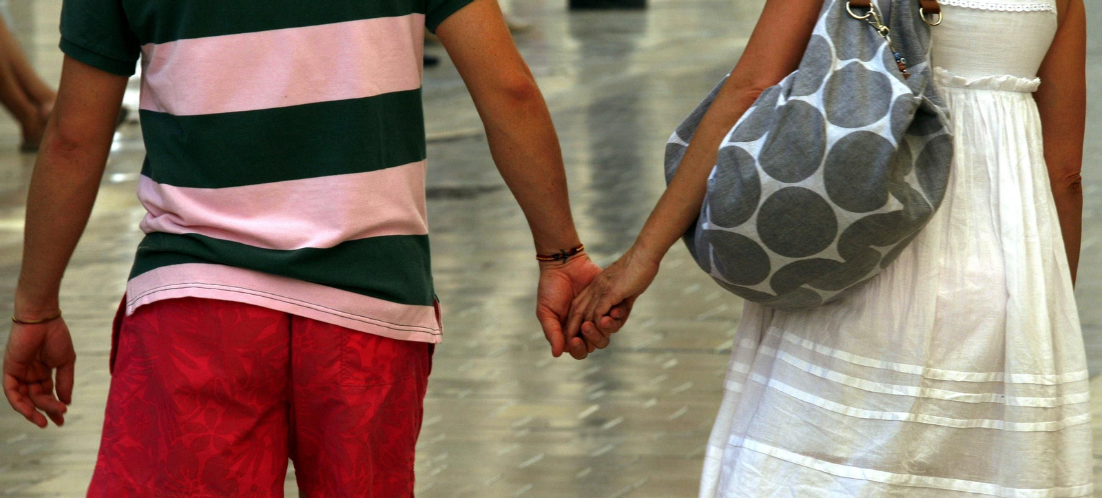 Una pareja cogida de la mano en verano.
