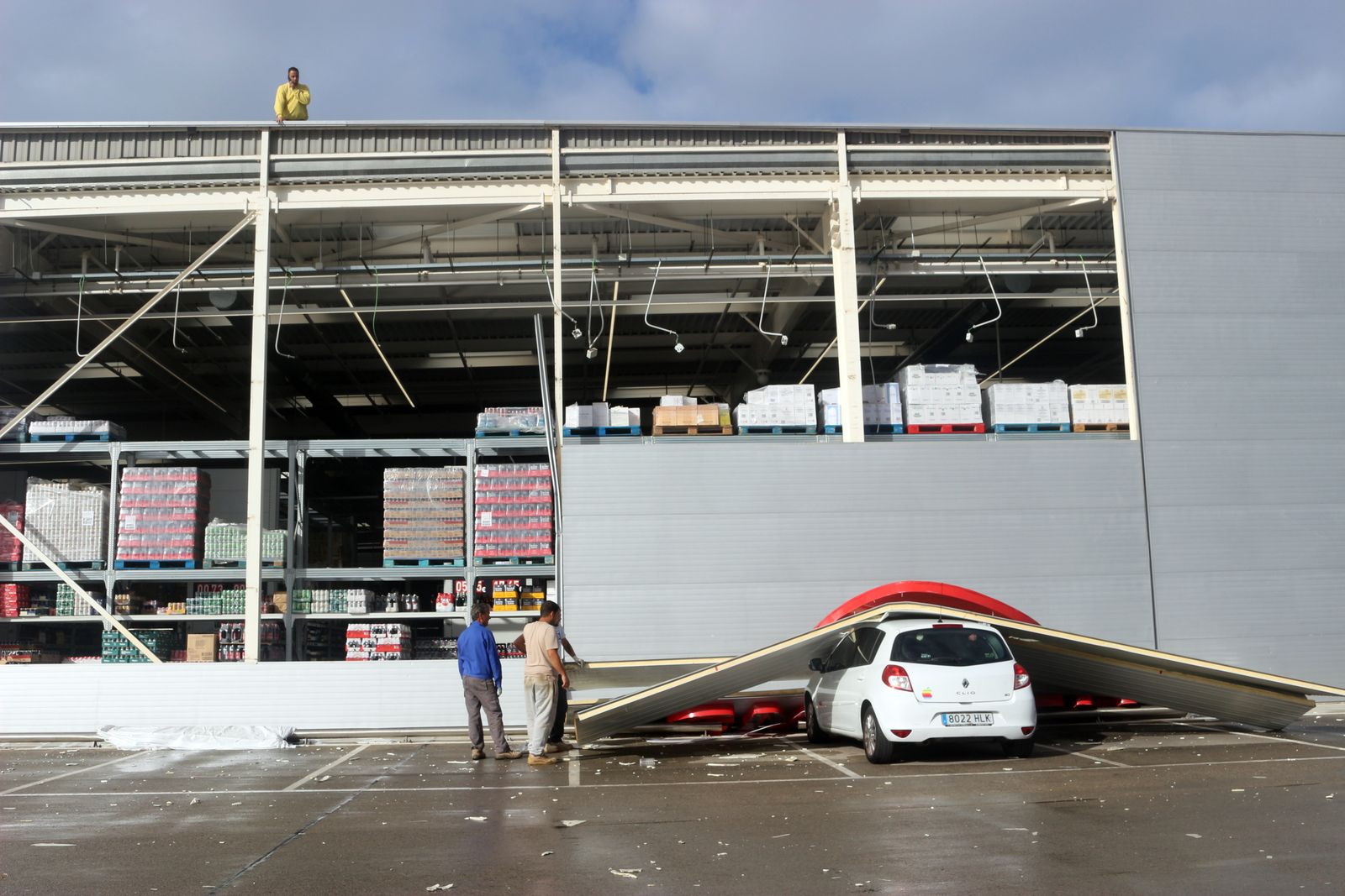 Trabajadores retiran las planchas que cayeron al parking del supermercado