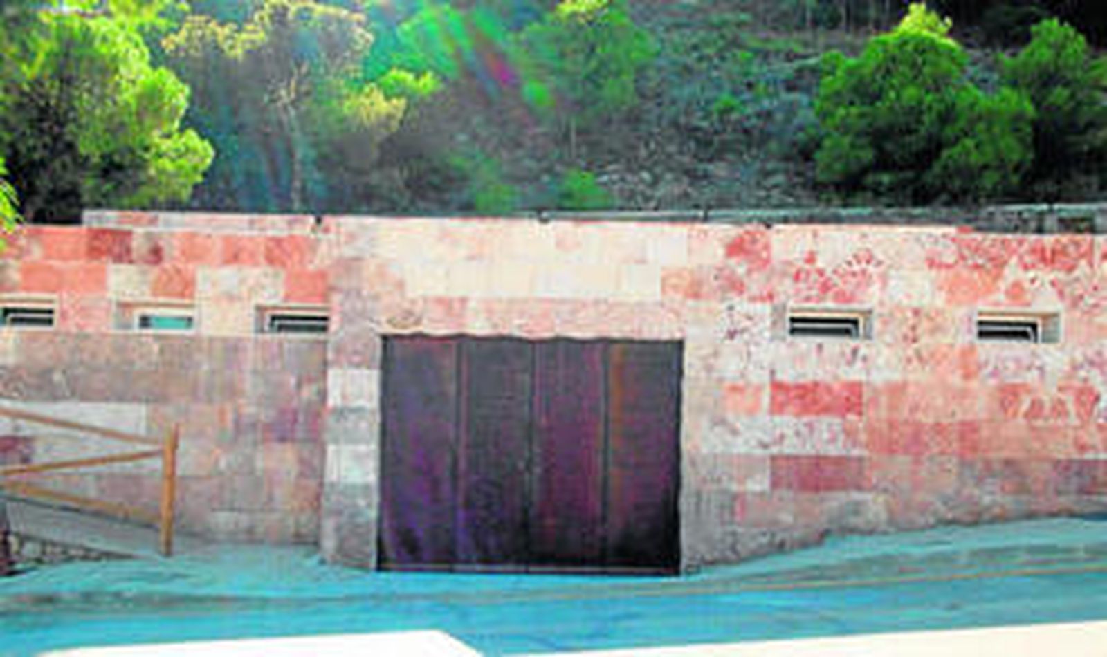 El edificio se ubica junto a un salto de agua natural conocido como 'La cascada' y frente a la Piscina Municipal y el IES Cerro Milano.