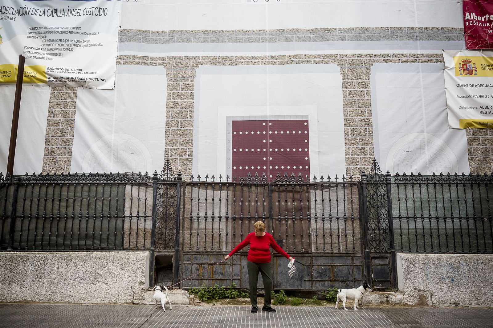 Una mujer paseando a dos perros en los alrededores de la Iglesia castrense