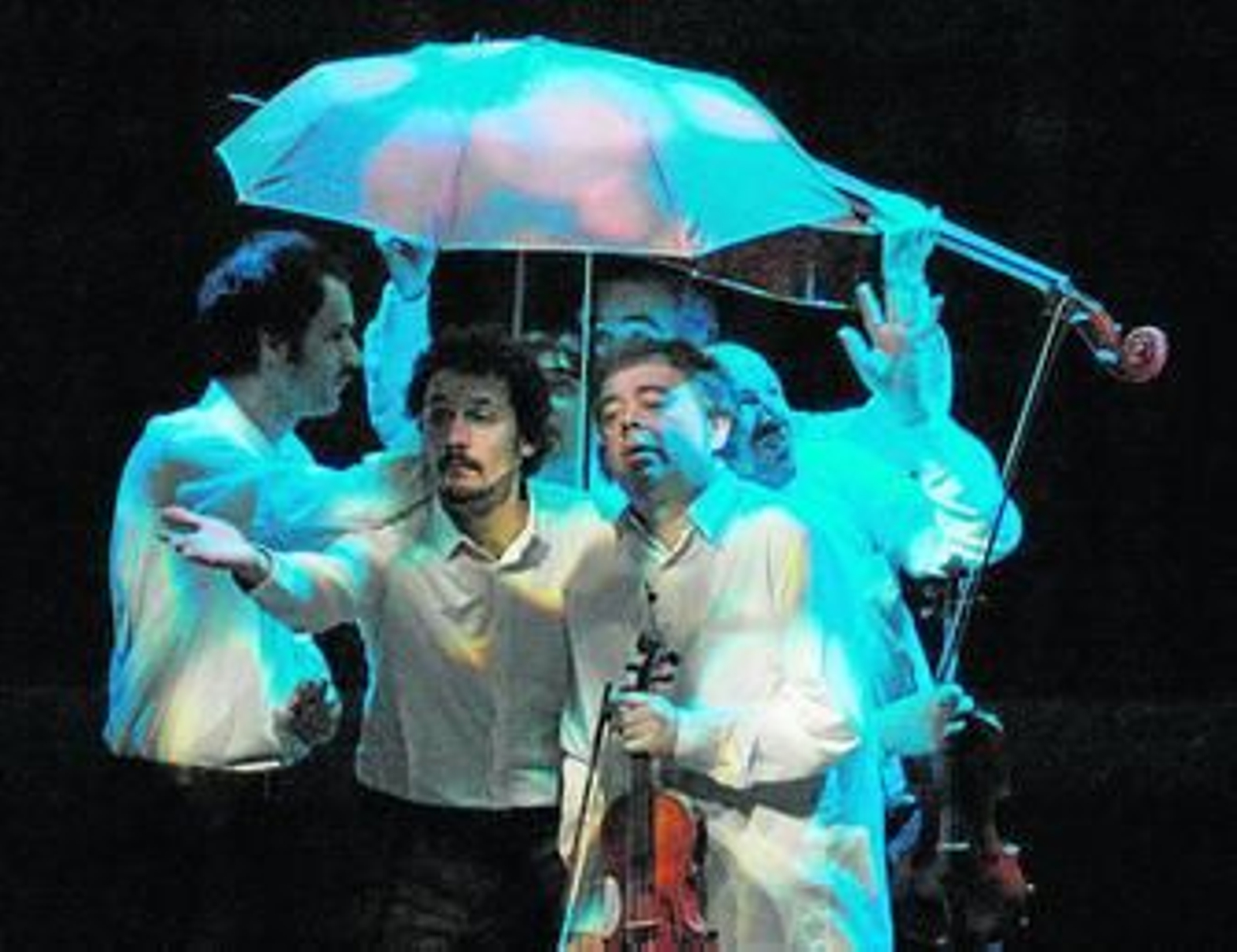 Varios de los músicos se protegen de una lluvia imaginaria.