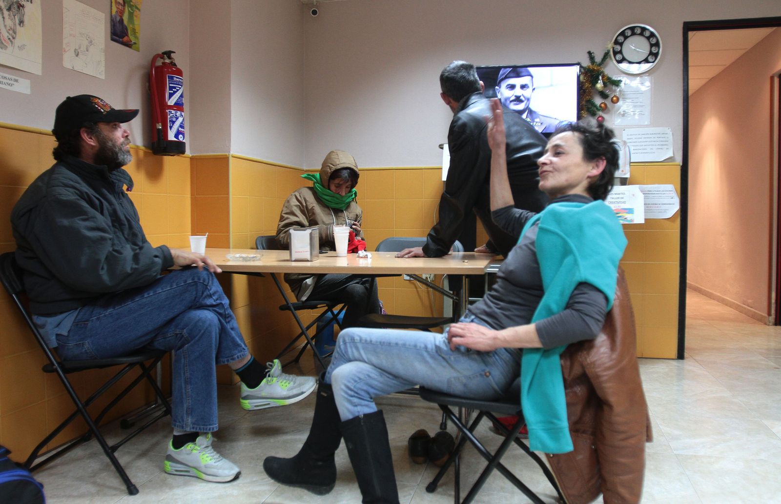 1. Los usuarios en el salón donde por el día juegan a las cartas, leen o ven la televisión. 2, 3 y 6. En el centro también se pueden poner lavadoras, asearse o utilizar los ordenadores. 4. Una joven se pone los guantes antes de salir a la calle. 5. Una de las usuarias del centro, María Ángeles con el coordinador, Alberto Fernández. 7. También hay taquillas donde guardan sus cosas.