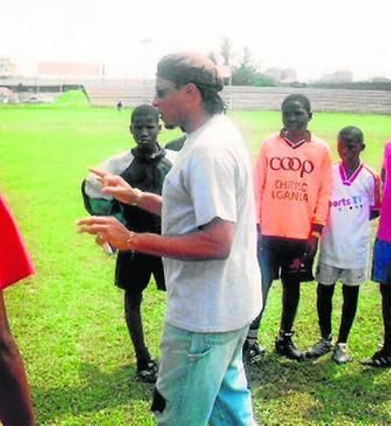 Makanaky hablando con jóvenes en un campo de fútbol en Uganda.