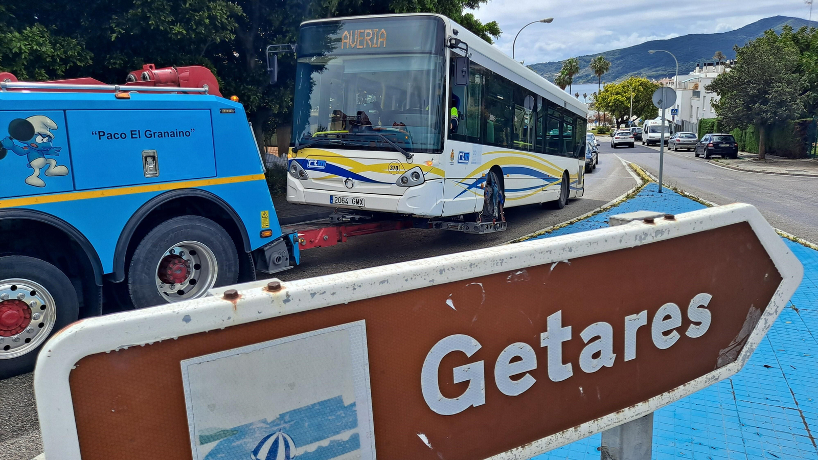 El autobús de la línea 2 es remolcado por una grúa a la salida de Getares.