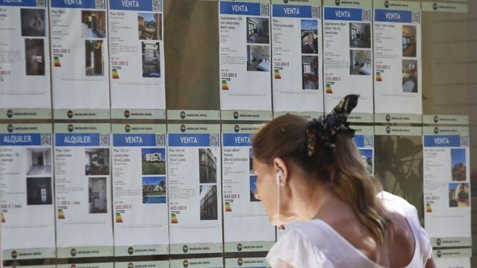 Una mujer observa el escaparate de una inmobiliaria.