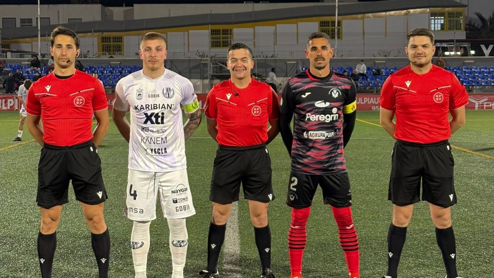 Los dos capitanes de ambos equipos junto con el trío arbitral.