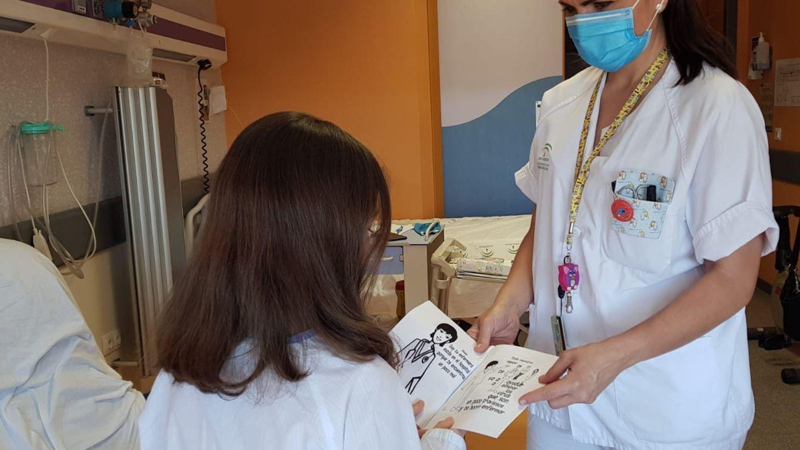 La enfermera Rocío Cordero entregándole a una menor el cuento y comentándolo con ella.