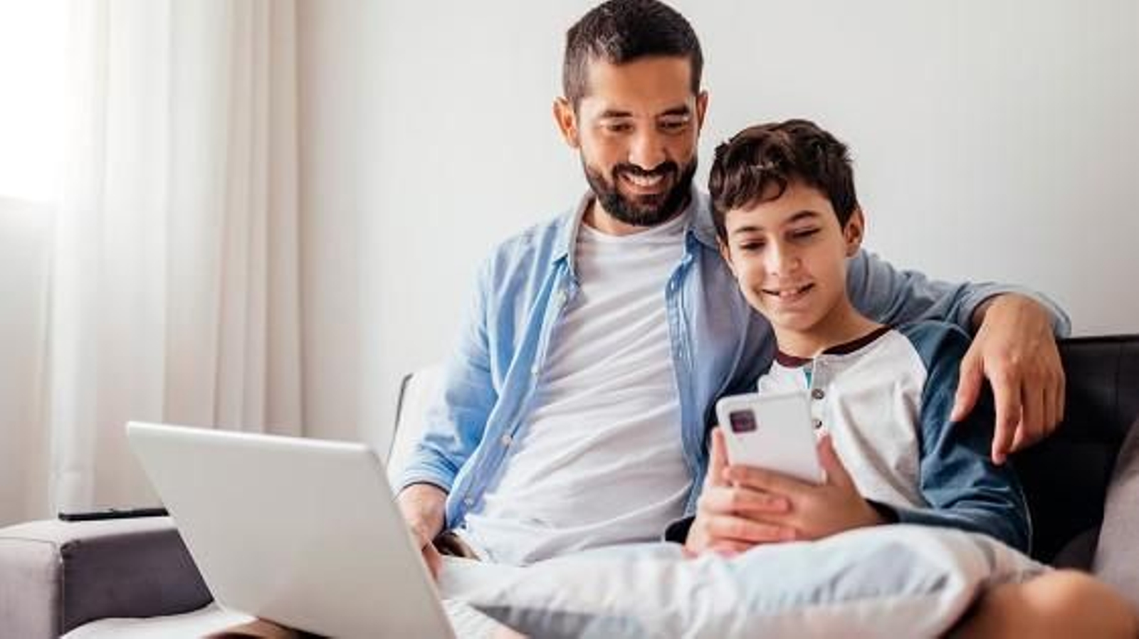 Menor usando la app de BBVA en el smartphone junto a su padre.