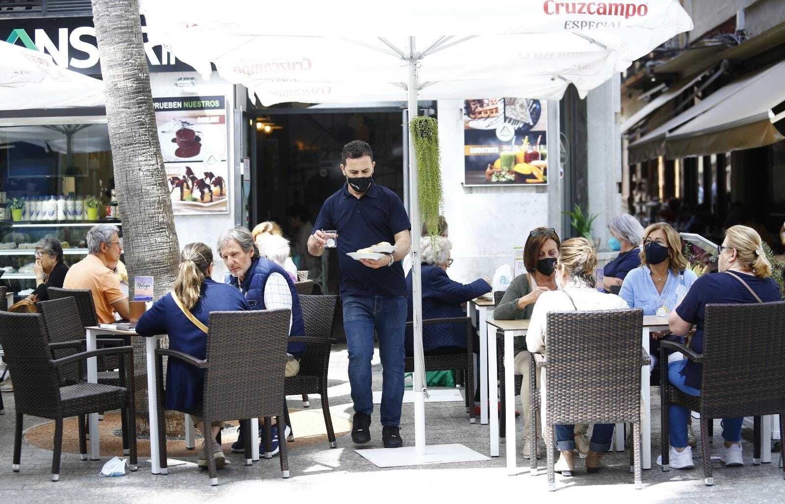 Un camarero atiende la terraza de un establecimiento de hostelería en Málaga.