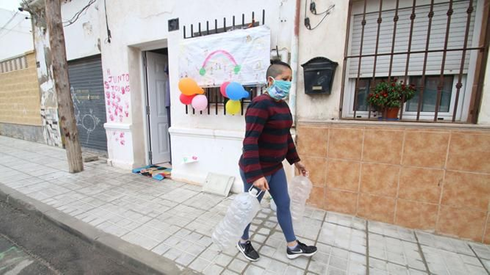 Una mujer pasa sale de la casa que ocupa junto a sus cuatro hijos menores en el barrio almeriense de El Puche.