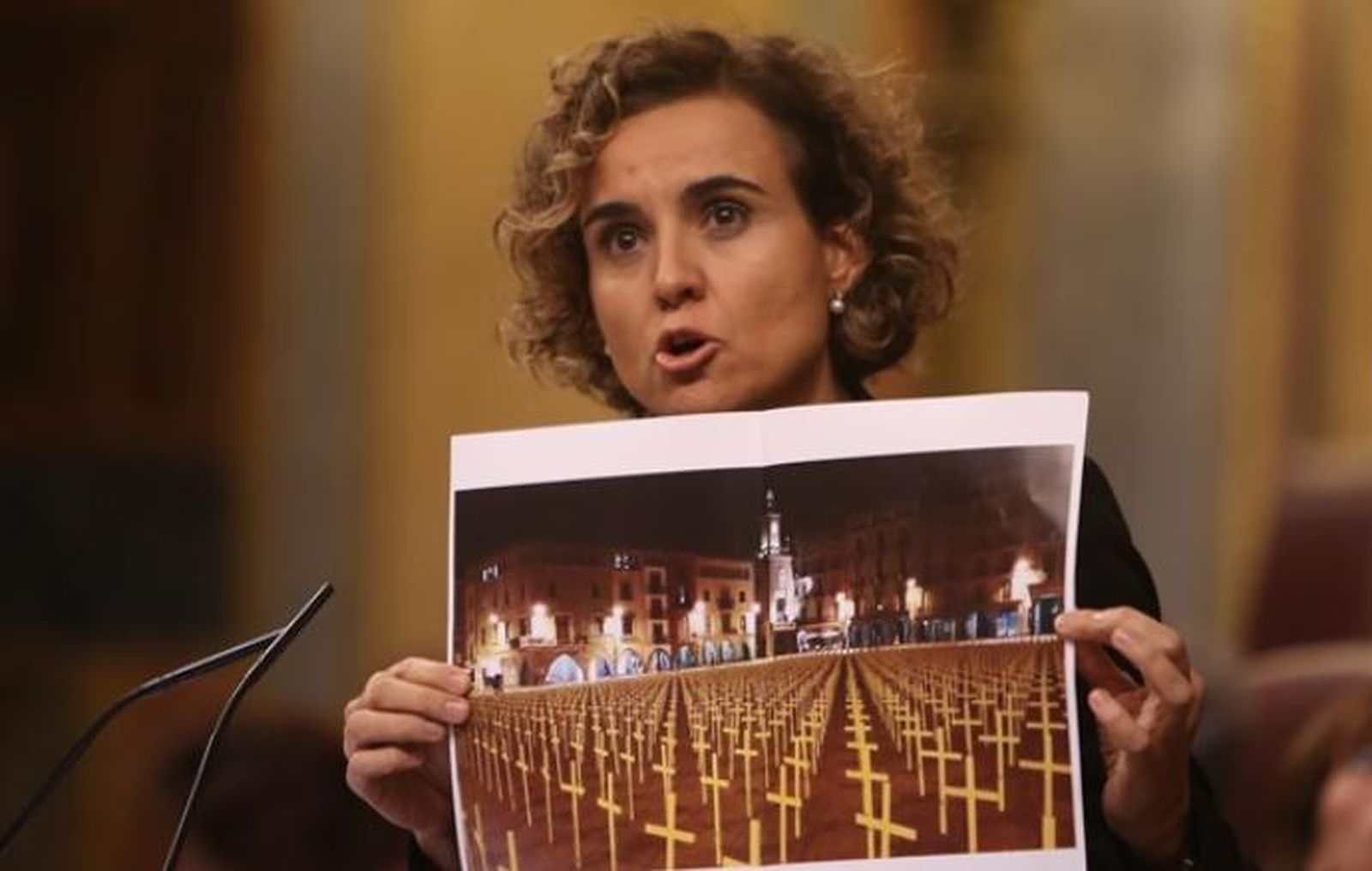Dolors Montserrat mostrando una imagen de una plaza repleta de cruces amarillas.
