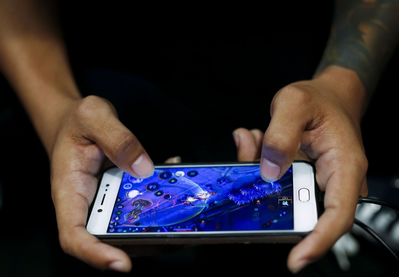 Un joven jugando 'on line' en un teléfono móvil.