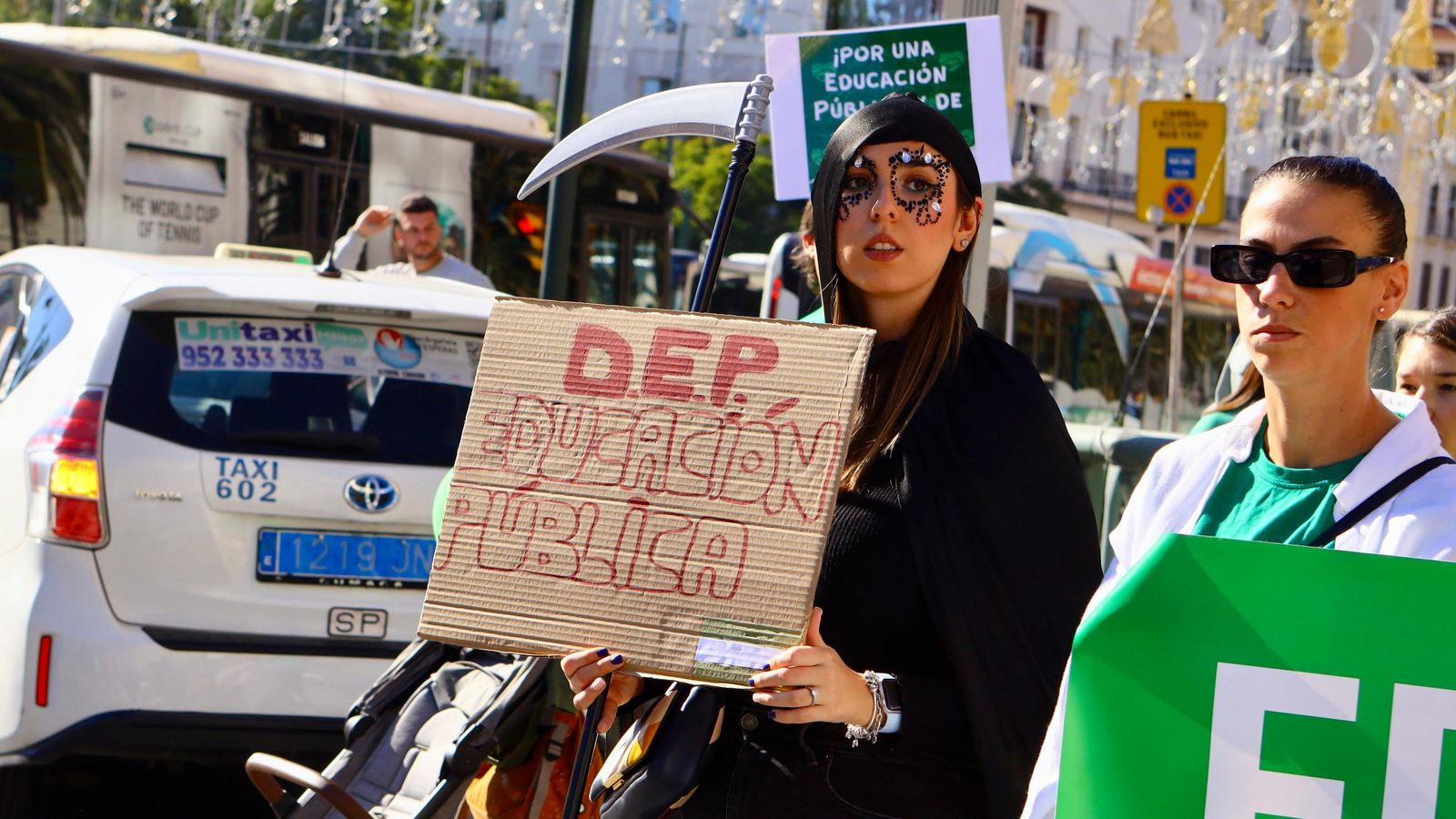 Una manifestante vestida de la parca con un cartel que declara muerta a la educación pública.
