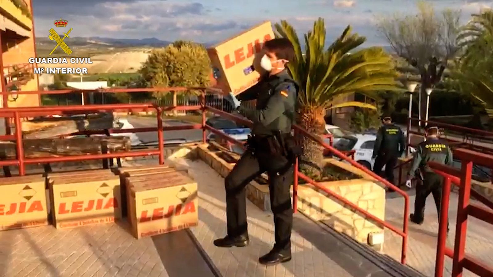 Un agente de la Guardia Civil transporta una caja de lejía para la residencia.