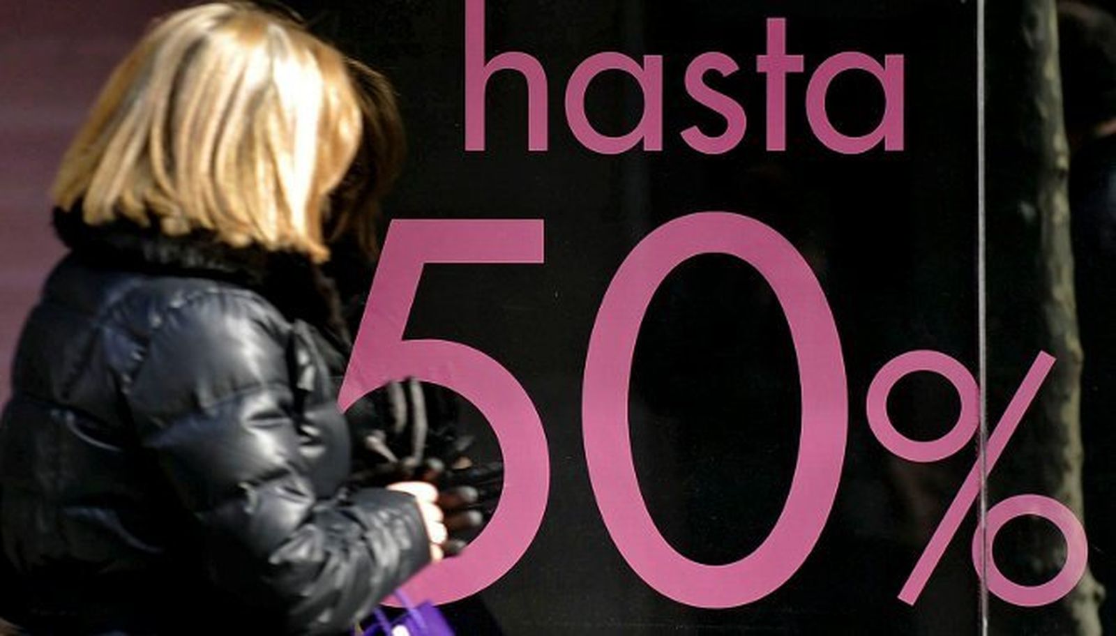 Una mujer pasa frente a un escaparate con el 50% de descuento.