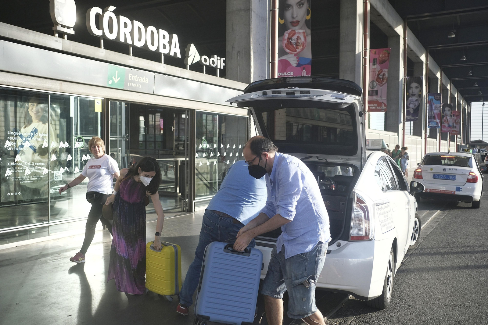 Unos turistas llegan en taxi a la estación de tren.