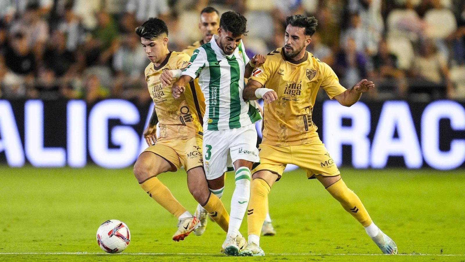 Calderón intenta marcharse entre dos jugadores del Málaga durante un partido con el Córdoba CF.