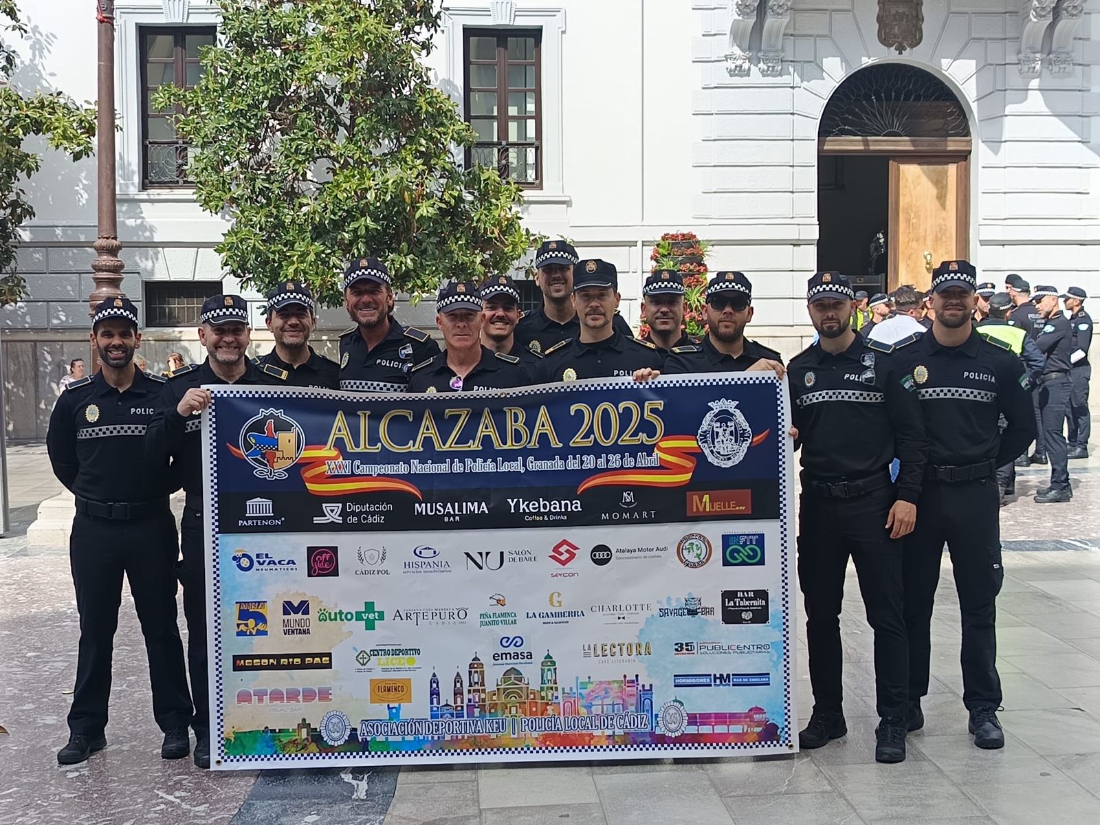 Los policías locales participantes, posan con la lona de los patrocinadores