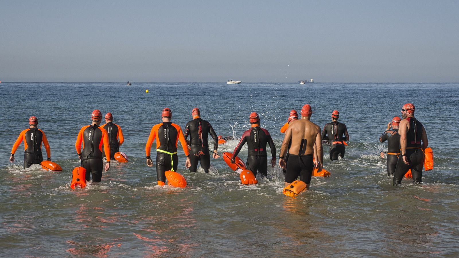El grupo de nadadores, entrando en el mar para iniciar la travesía en aguas abiertas.