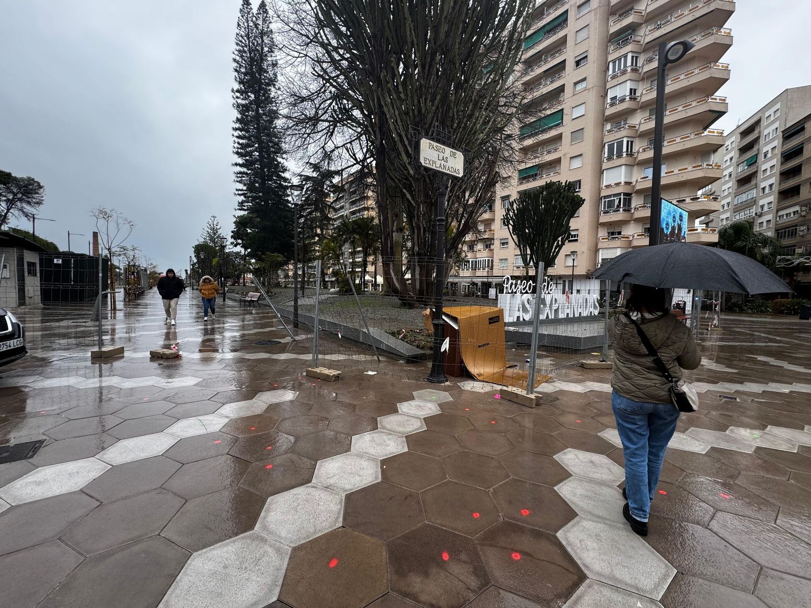 Varias personas por el Paseo de las Explanadas con las vallas metálicas y las losetas defectuosas marcadas