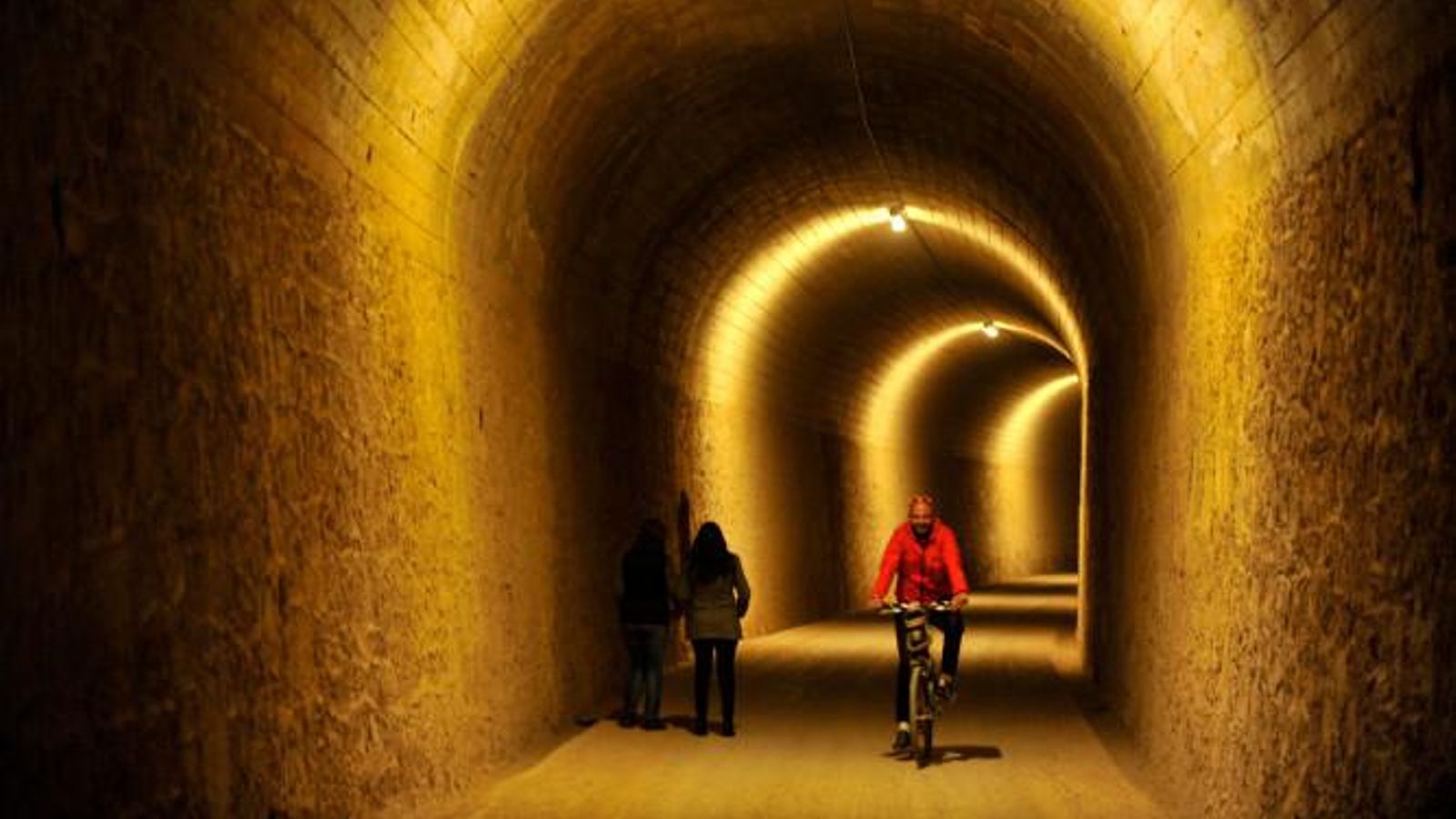 Ciclista y peatón se cruzan por uno de los túneles más largos de la vía Verde Vía Verde.