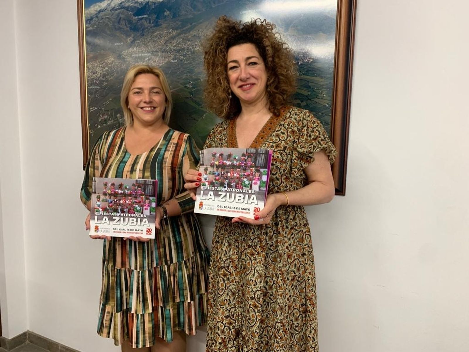 La alcaldesa y la concejala de Fiestas de La Zubia posan con el cartel de las fiestas