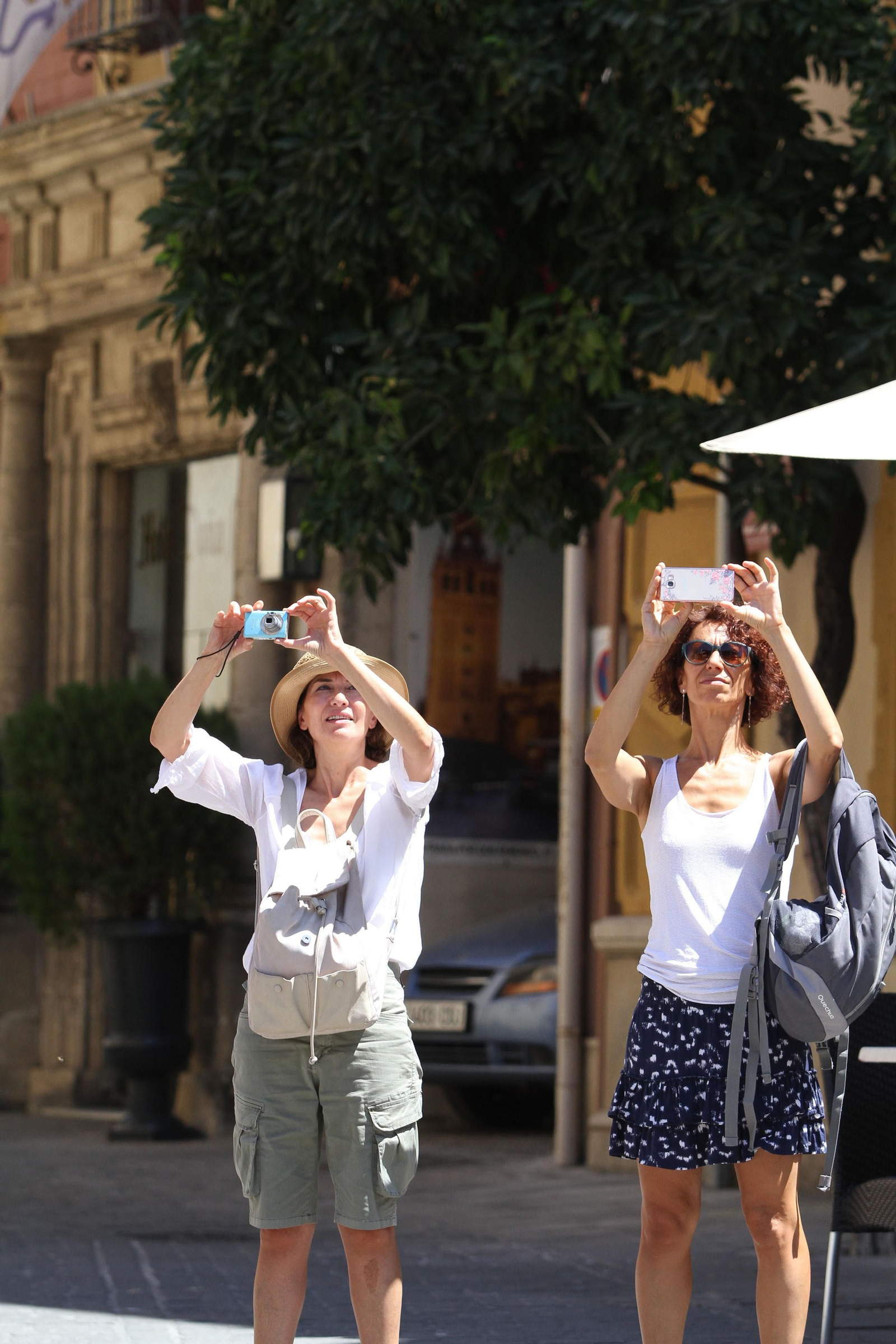 Dos turistas hacen fotos de la Giralda con sus móviles.