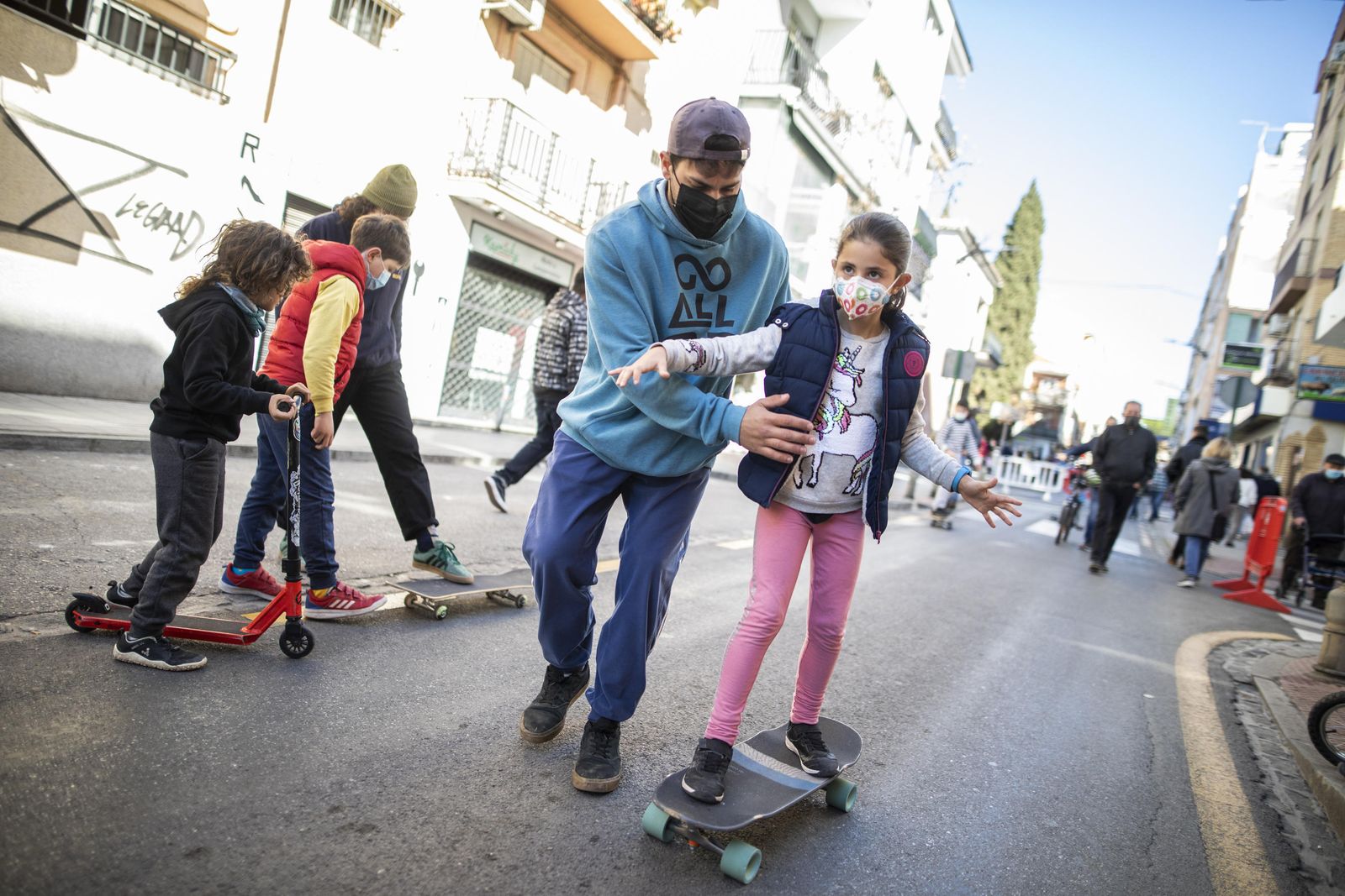 Un adolescente enseña a una niña a montar en skate