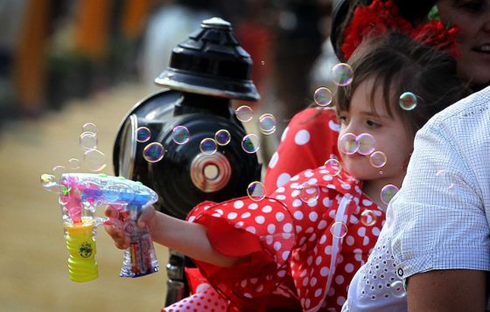 Una pequeña vestida de flamenca se divierte haciendo pompas de jabón.

Foto: miguel ángel gonzález