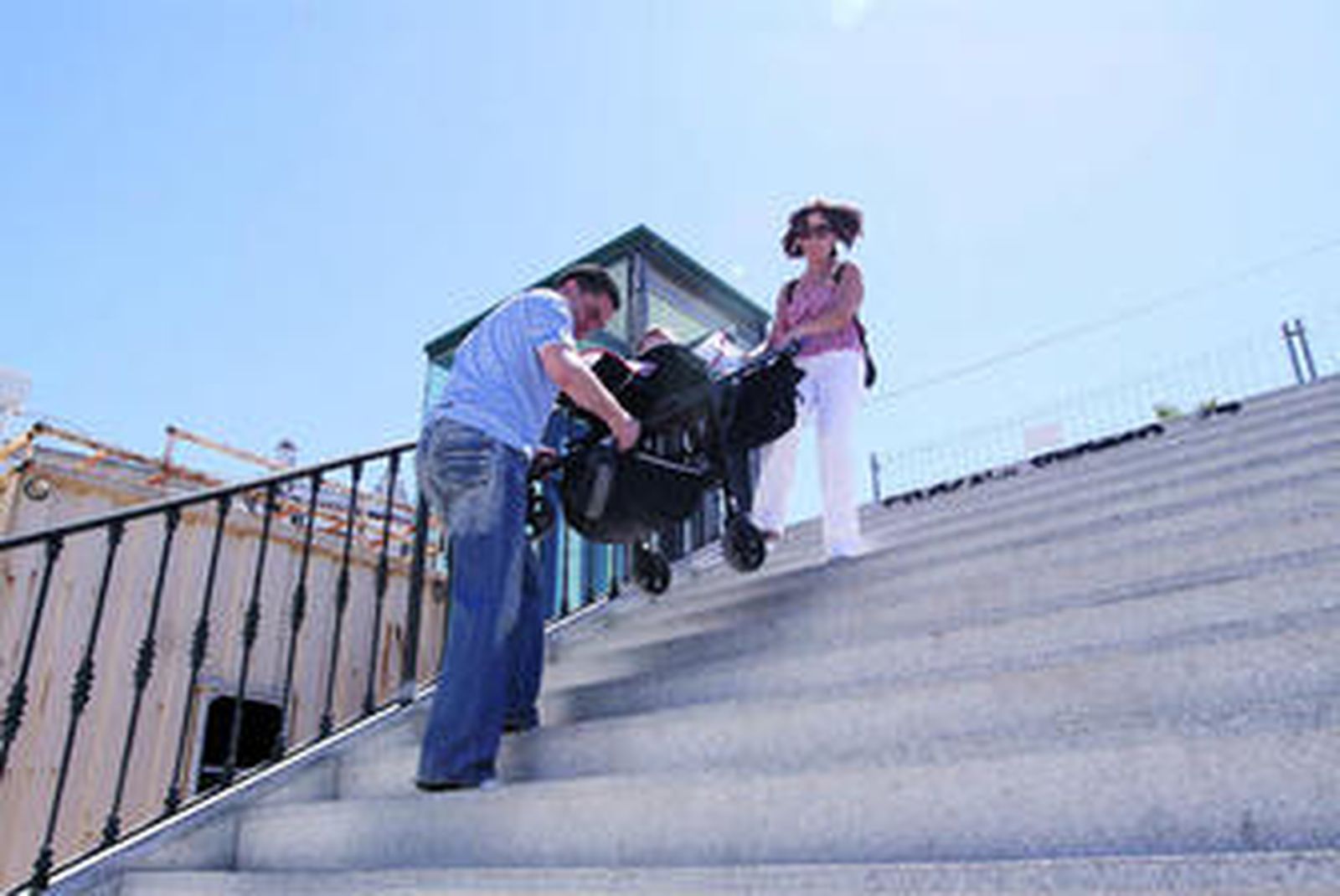 Una mujer recibe ayuda para bajar con el carrito de bebé.