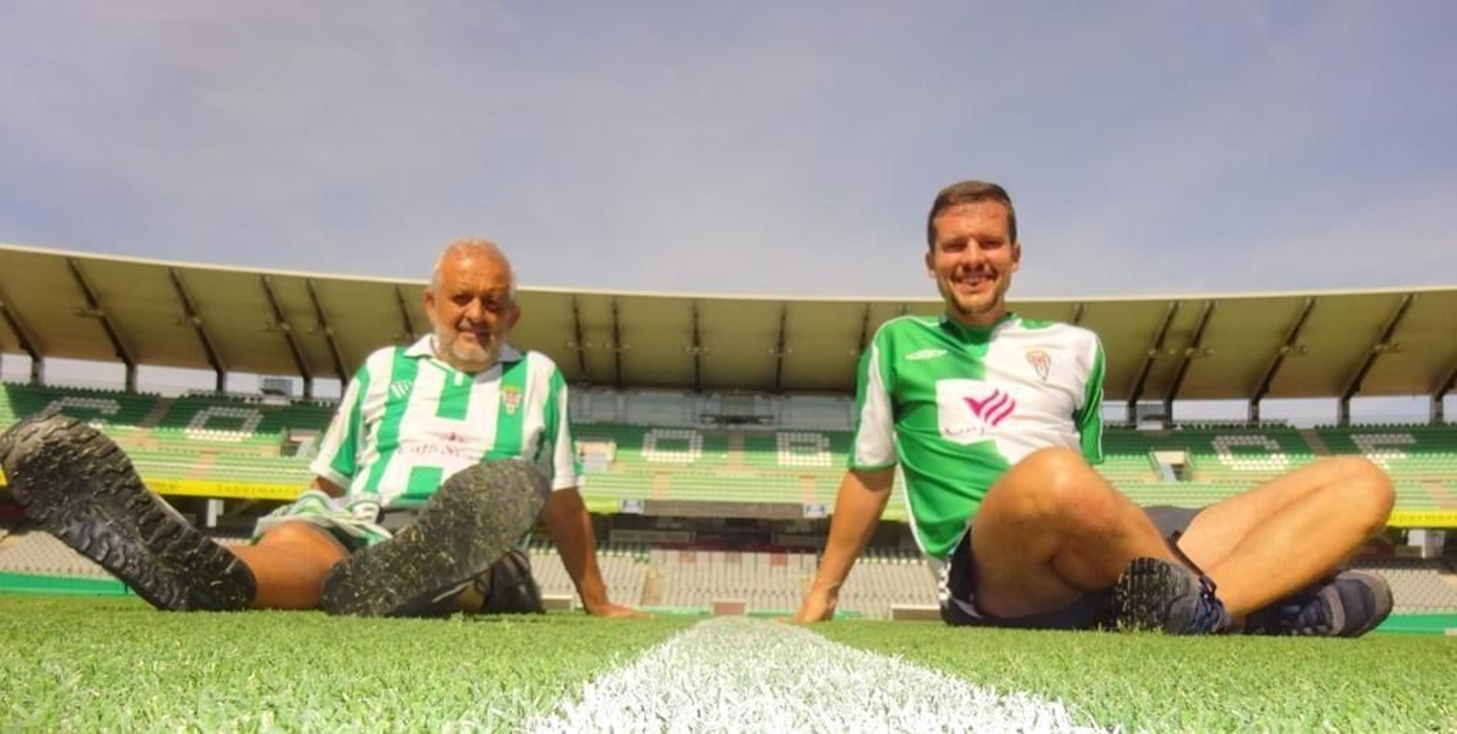 Dos abonados del Córdoba CF posan sobre el césped de El Arcángel tras renovar sus abonos.