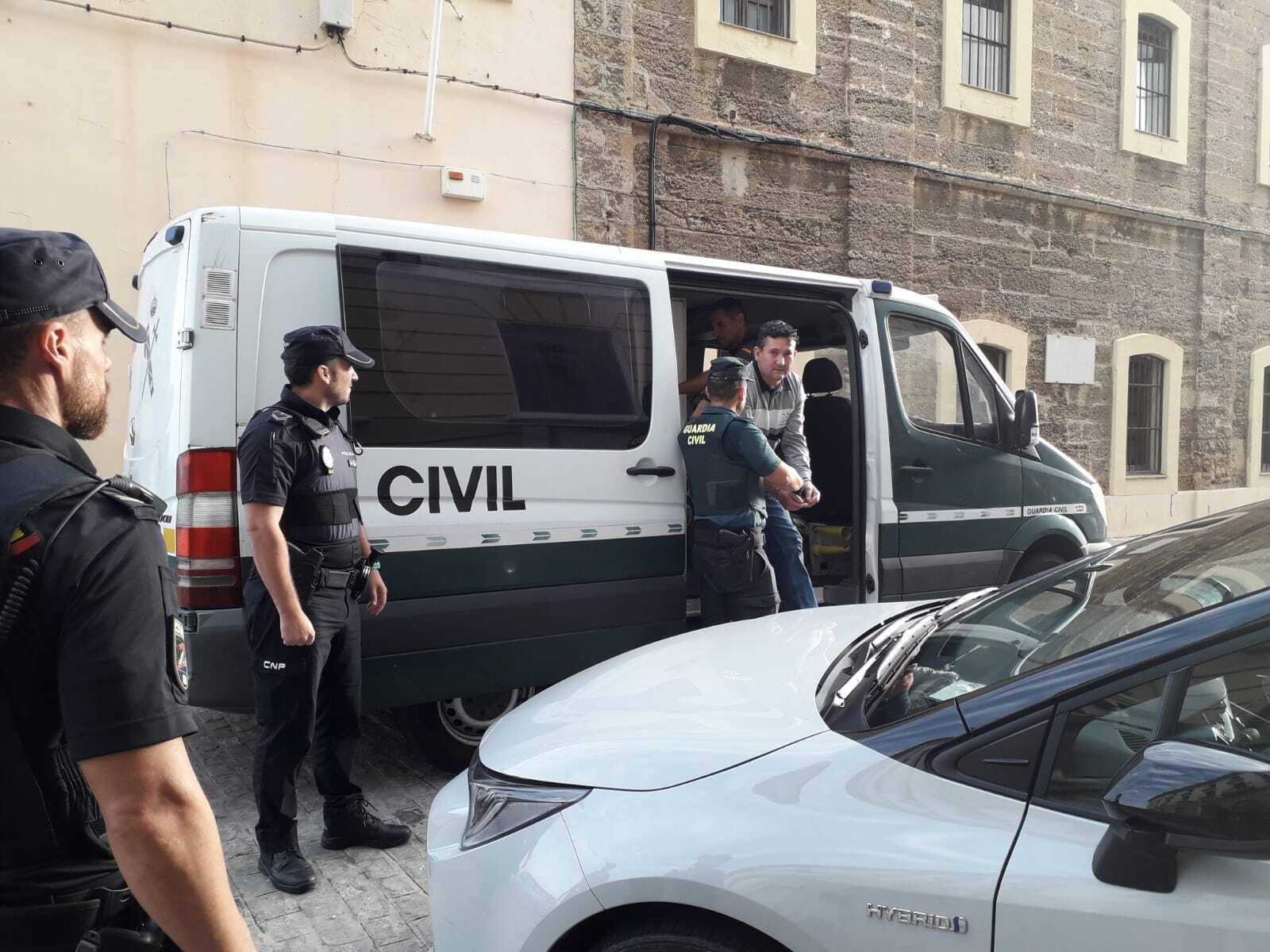 El acusado sale del furgón policial esposado antes de entrar a juicio.