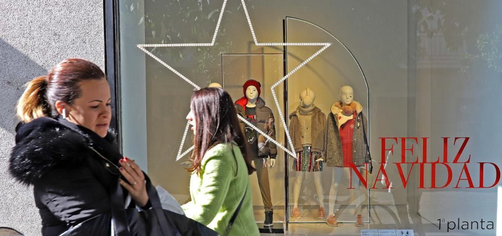 Dos mujeres pasan esta semana ante un escaparate del centro con decoración navideña.