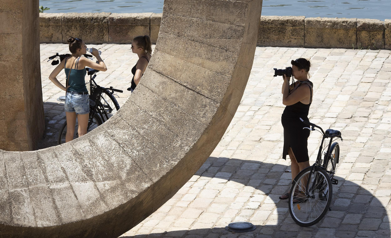 Una mujer hace una foto mientras otras dos charlan en el entorno del río.
