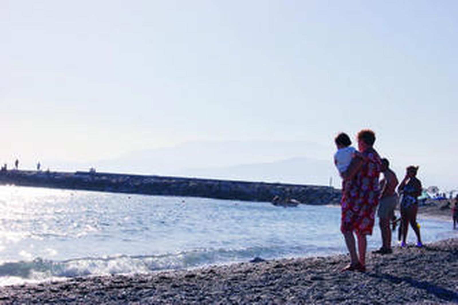 Una mujer sostiene a su nieto en brazos, una estampa típica del verano.