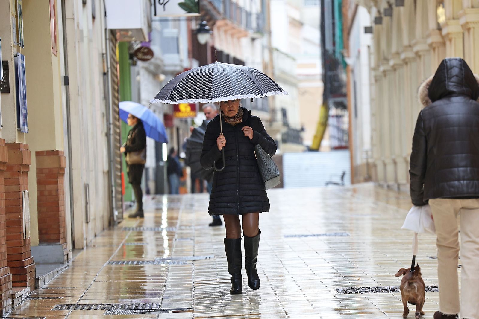Una persoan se refugia de la lluvia en Huelva.