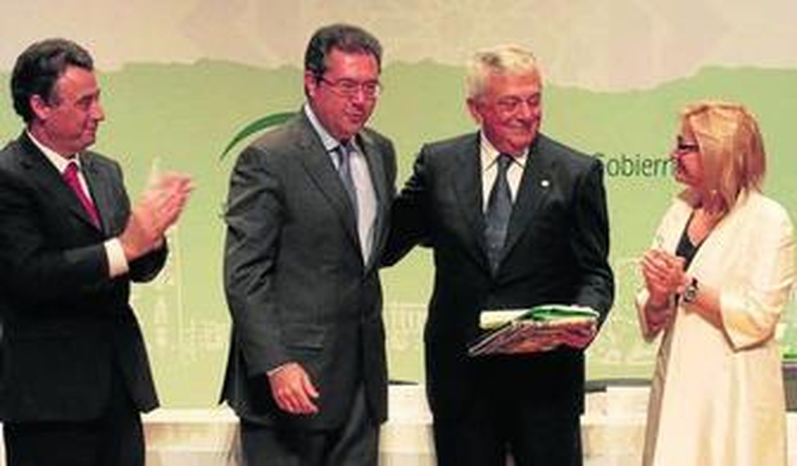 Francisco Herrero recibe la distinción flanqueado por Juan Espadas y Carmen Tovar.