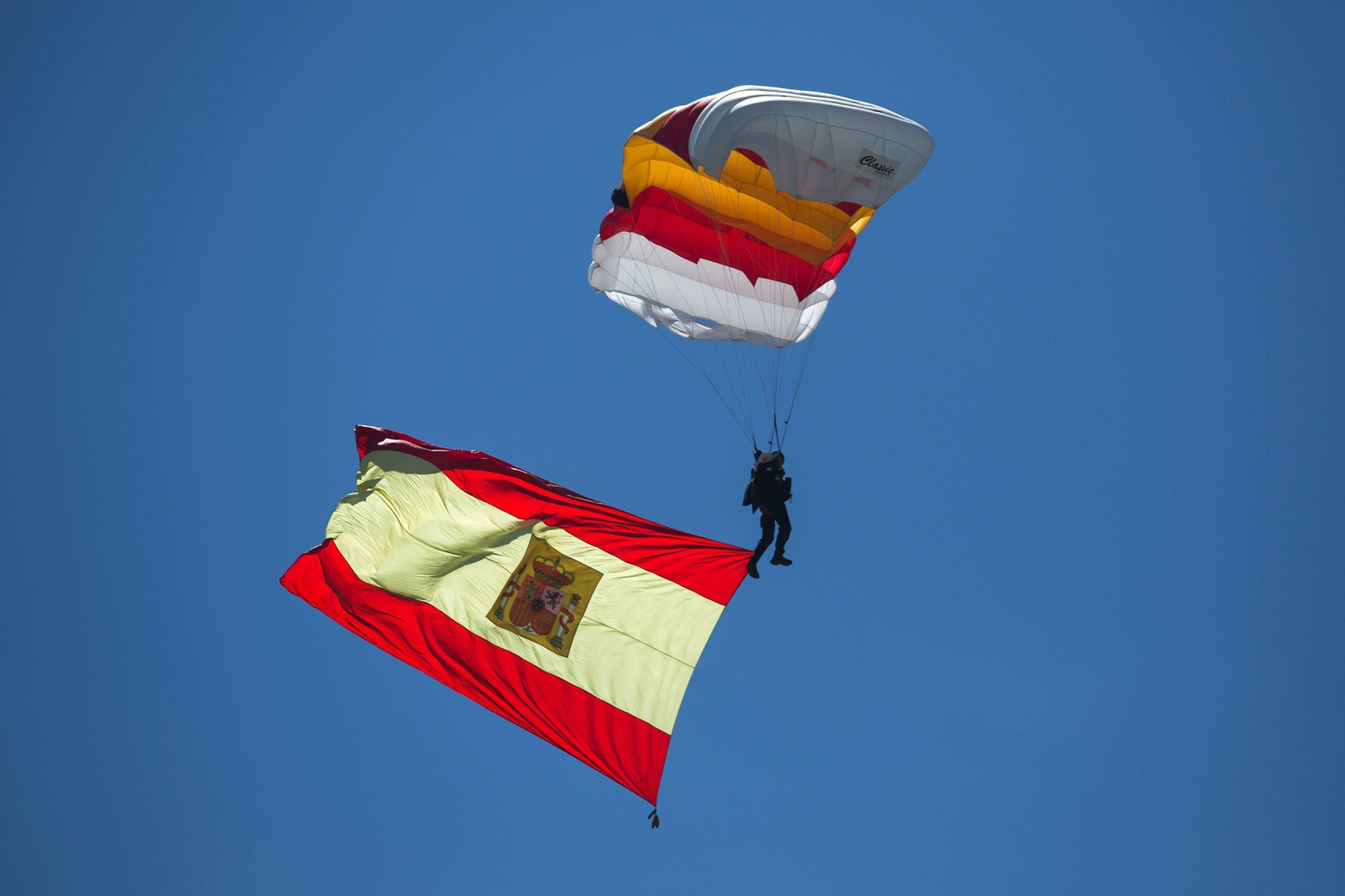 Un paracaidista desciende en el cielo malagueño con la bandera de España.