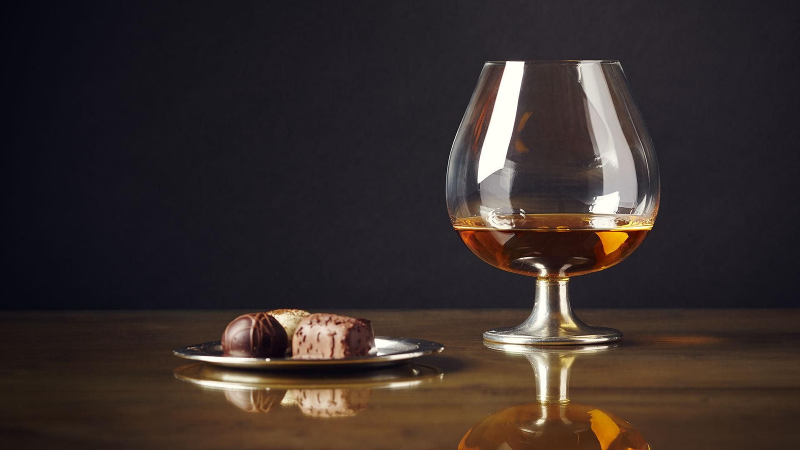 Una copa de brandy acompañada de unos bombones.