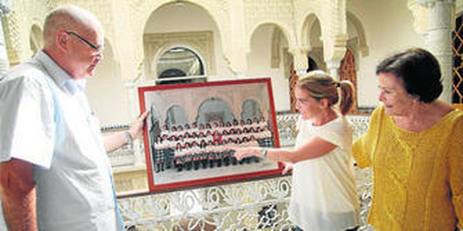 Popi Argudo señala a Inés en la foto de su promoción de la Compañía de María, junto a la señorita Angelines y don Andrés, en las instalaciones del colegio.