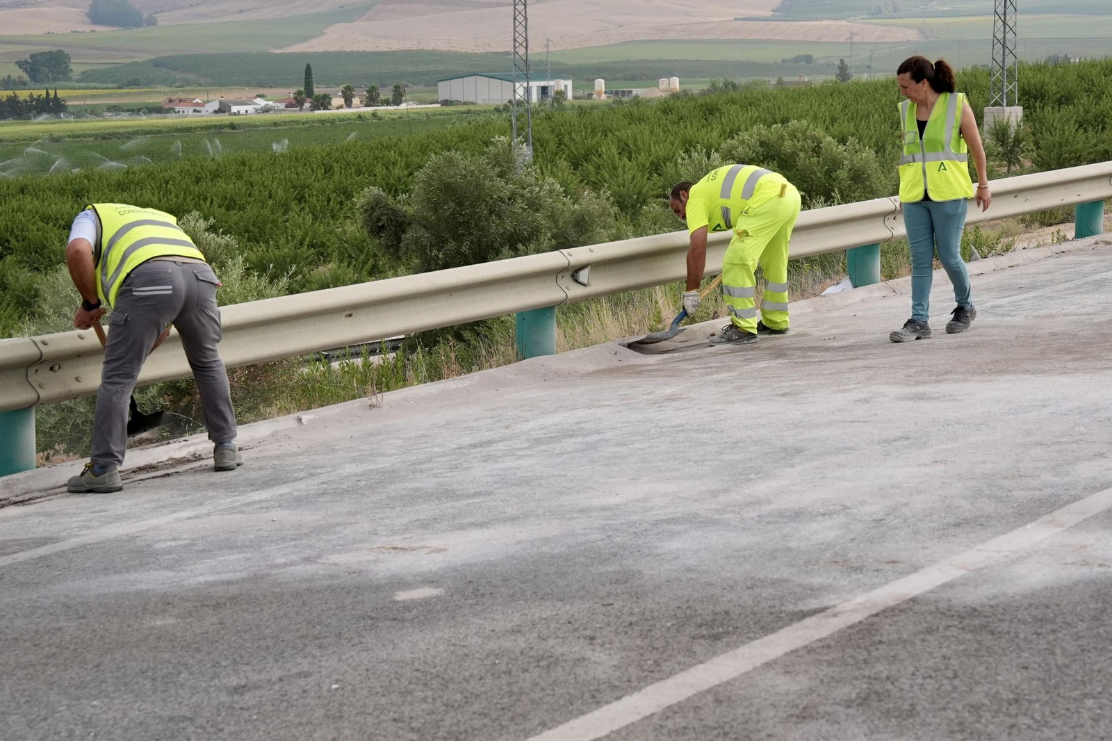 Operarios de mantenimiento de carreteras limpian los restos del accidente donde tres personas han fallecido y una ha resultado herida grave al chocar frontalmente dos vehículos en una carretera de Arcos