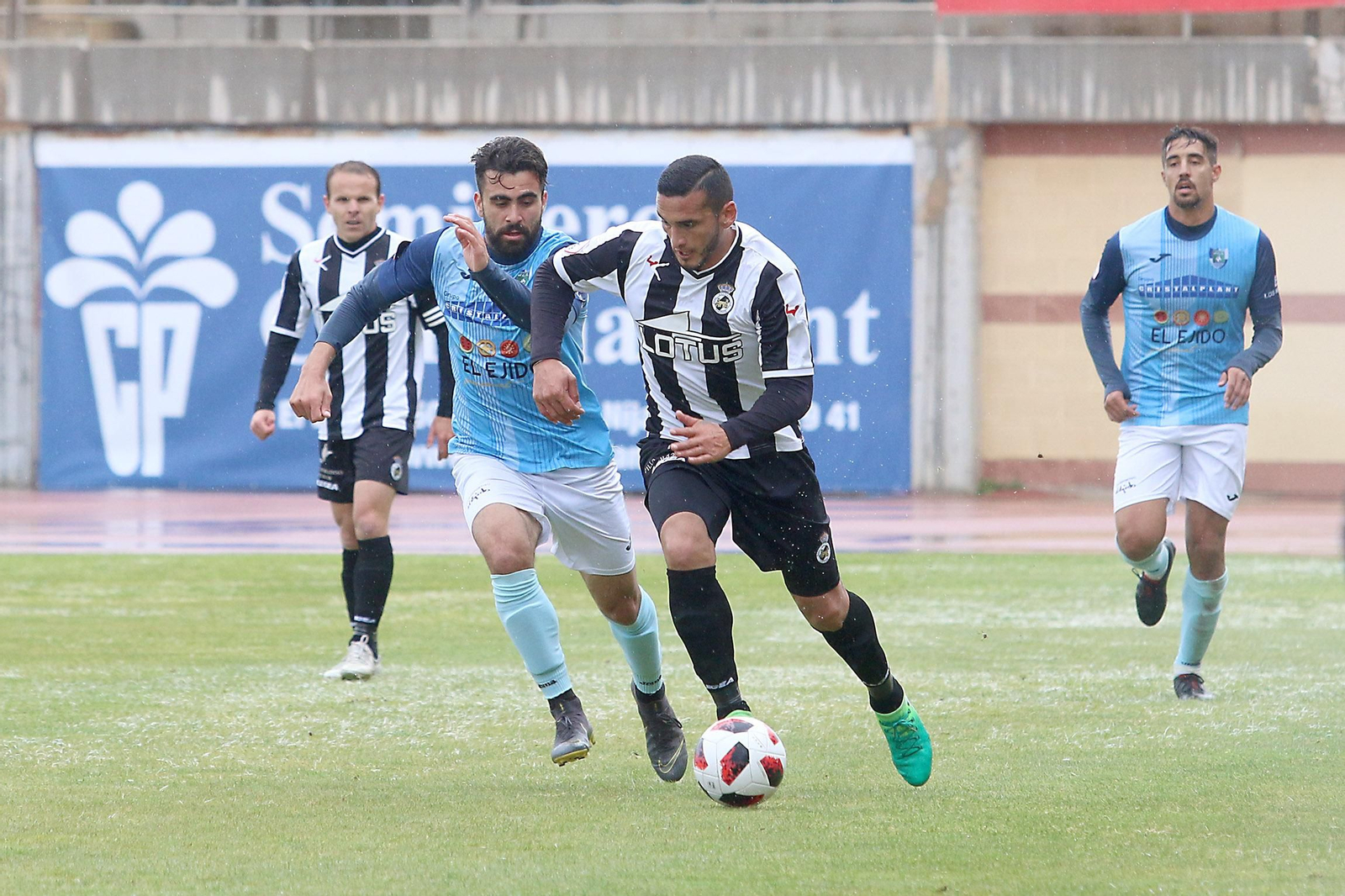 El albinegro Gastón Cellerino pugna bajo la lluvia con un rival.